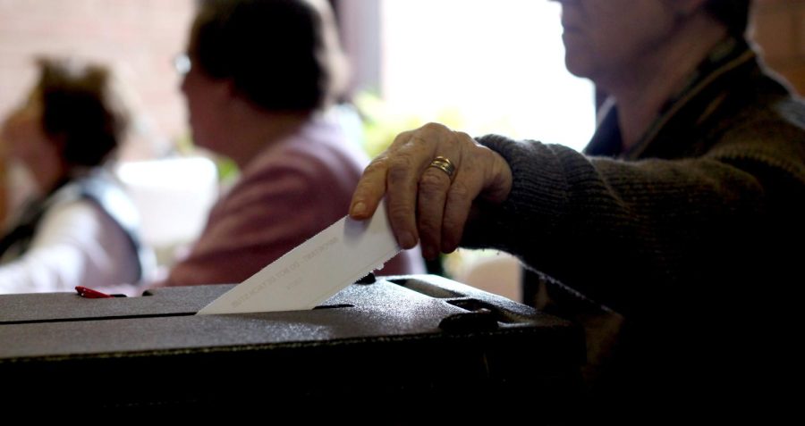 Retired nurse Sally Crane drops a part of a voter’s ballot into the ballot box during the Ohio Primary election at the Presbyterian Church on East Summit Street on Tuesday, March 15, 2016.