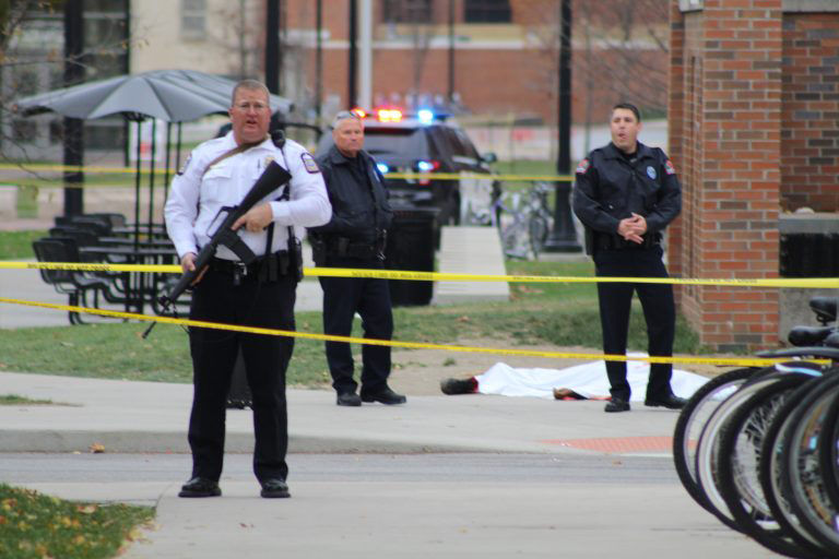 A police officer and two other emergency personnel stand near a body lying near the Chemical Biomolecular Engineering and Chemistry building on OSU's North Campus on Monday, Nov. 28, 2016. 