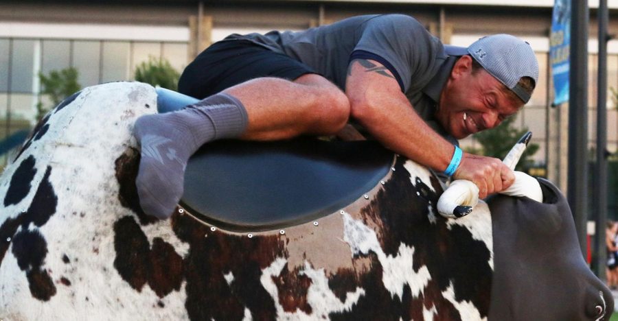 Graduate student Richie Schultz holds on tight while riding a mechanical bull during BlastOff in Risman Plaza on Sunday.