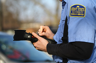 A close up of Parking Services employee Adam Nowicki as he issues a parking ticket for a vehicle parked in the wrong lot, Monday, March 10, 2014.