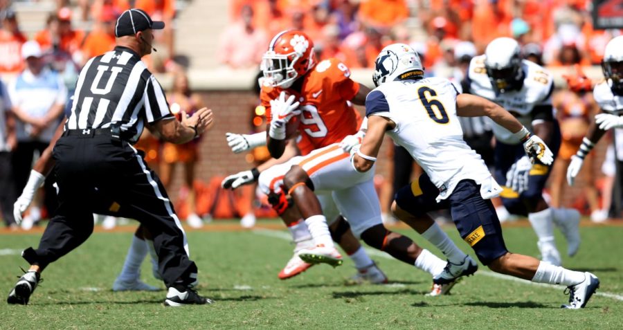 Clemson running back Travis Etienne speeds past defenders and into the referee during the second half.