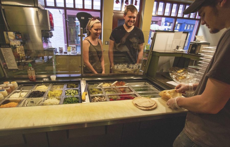 Employee Russell Baker makes pitas for customers Taylor Collett and Matt Mudd on Saturday, April 16, 2016 at Pita Pit in downtown Kent’s Acorn Alley.