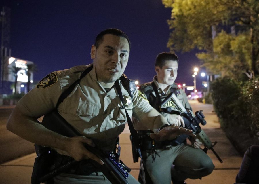 Police officers advise people to take cover near the scene of a shooting near the Mandalay Bay resort and casino on the Las Vegas Strip, Sunday, Oct. 1, 2017, in Las Vegas.