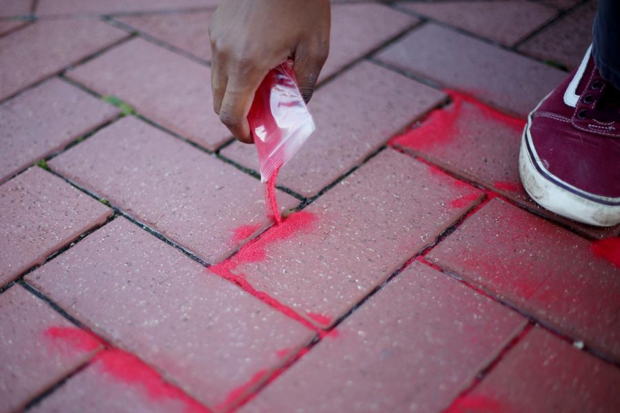 Mason McLeod, a junior psychology major, helps fill Risman Plaza with red sand to raise awareness on human trafficking Wednesday, Oct. 18, 2017.