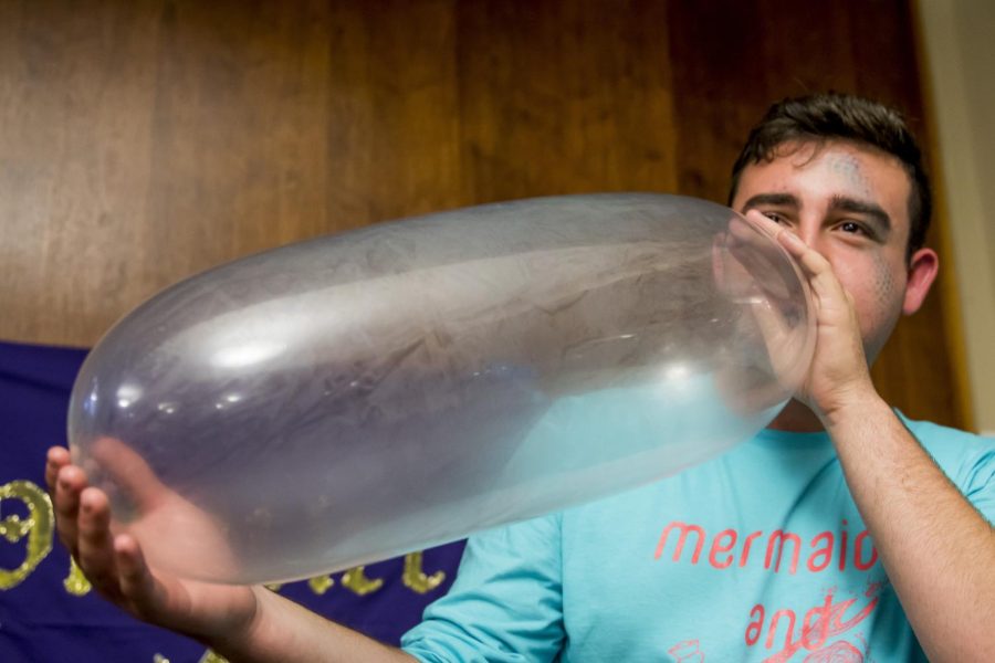 John Young, then a freshman entrepreneurship major, blows up a condom at Sextoberfest in the Tri-Towers Rotunda Friday, Oct. 21, 2016.