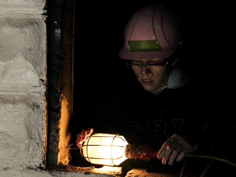 Monica Higgins, the secretary of Habitat for Humanity's Kent State chapter, adjusts a work light in the basement of a home in Kent, Saturday, Nov. 18, 2017. Higgins was one of several volunteers who worked to repaint a home for Denise Ramey and her daughter, Taylor, who are awaiting a new home. Denise and Taylor have both worked with volunteers on the renovations to pay into “sweat equity,” a part of the Habitat for Humanity home-owning process, which encourages future homeowners to aid in the construction of their future home. 