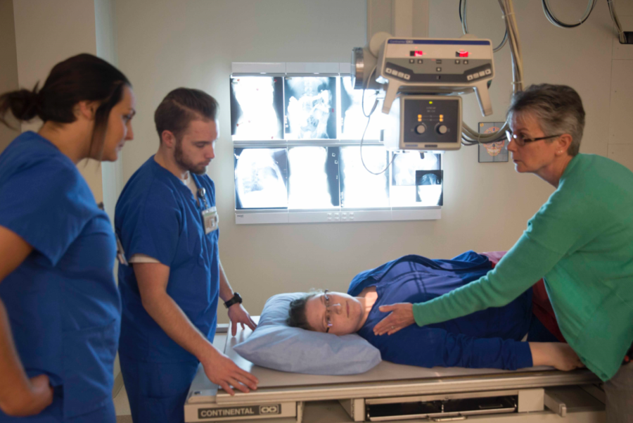 Recent graduates of the Kent Salem Radiology program reviewing radiologic procedures in a lab with clinical cordinator Judy Miller. 