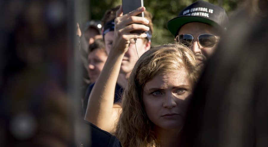 Kaitlin Bennett, a Kent State alumna and an organizer of the open-carry walk, stands behind Ohio State Highway Patrolmen as she talks with counterprotesters in the Schwartz Center parking lot on Sept. 29, 2018.