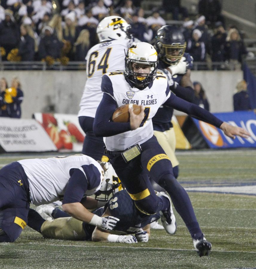 Kent State freshman quarterback Dustin Crum breaks a tackle among Akron’s defenders Tuesday, Nov. 21, 2017.