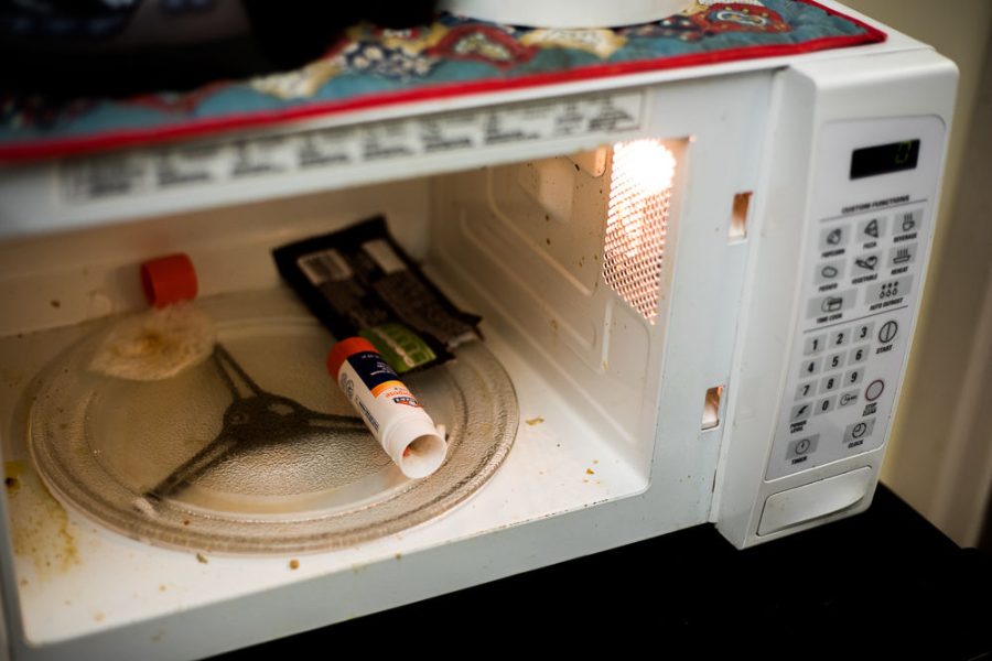 The remnants of a candy wrapper and a glue stick sit inside a microwave in Satterfield Hall on Tuesday, Dec. 18, 2018.