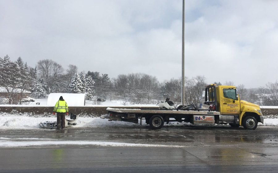 A tow truck driver picks up the remaining debris on SR 8 in Stow following a semi truck crash Monday, Jan. 21, 2019. 