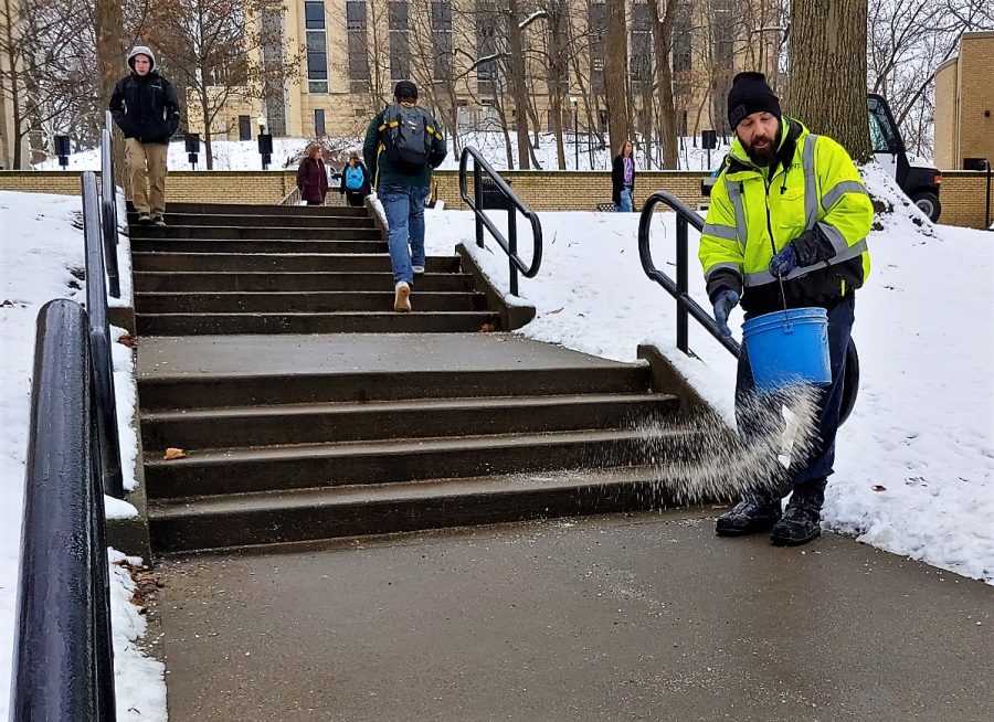 Andrew Britton, a groundskeeper, sprinkles salt on a staircase outside McGilvrey Hall Wednesday afternoon. 