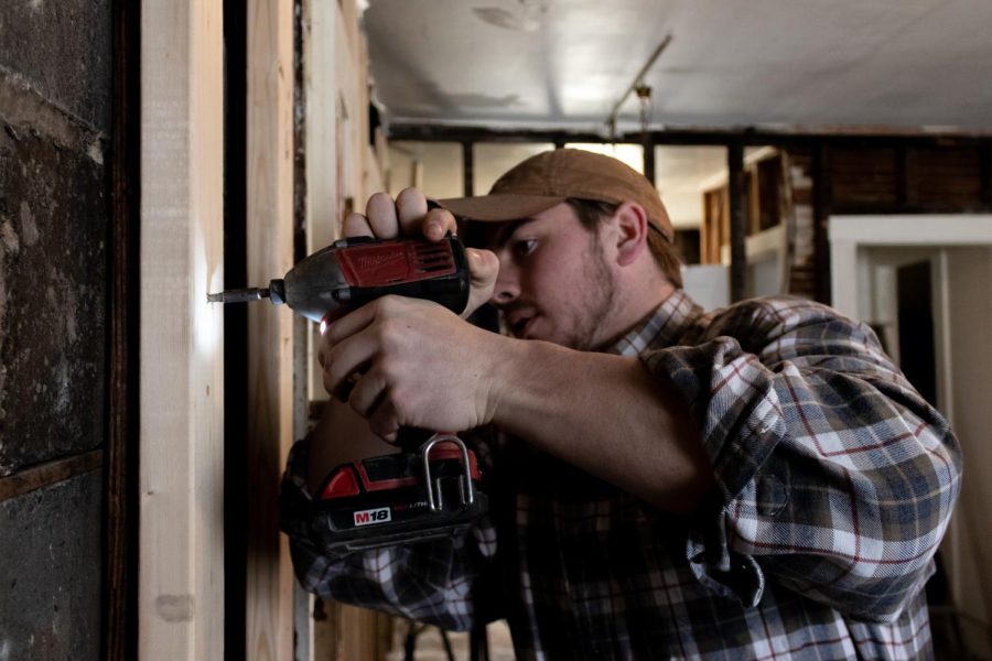 Freshmen construction management major Art Schuessler drills a stud in a wall at the Haven of Portage County. 