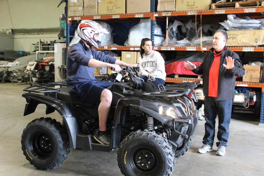 Nicole Albright,a Kent State alumna and an intern for DRR USA, Martin Iliev, a senior Kent State aeronautics major, listen to owner Lou Decuzzi explain the Stealth Electric ATV.