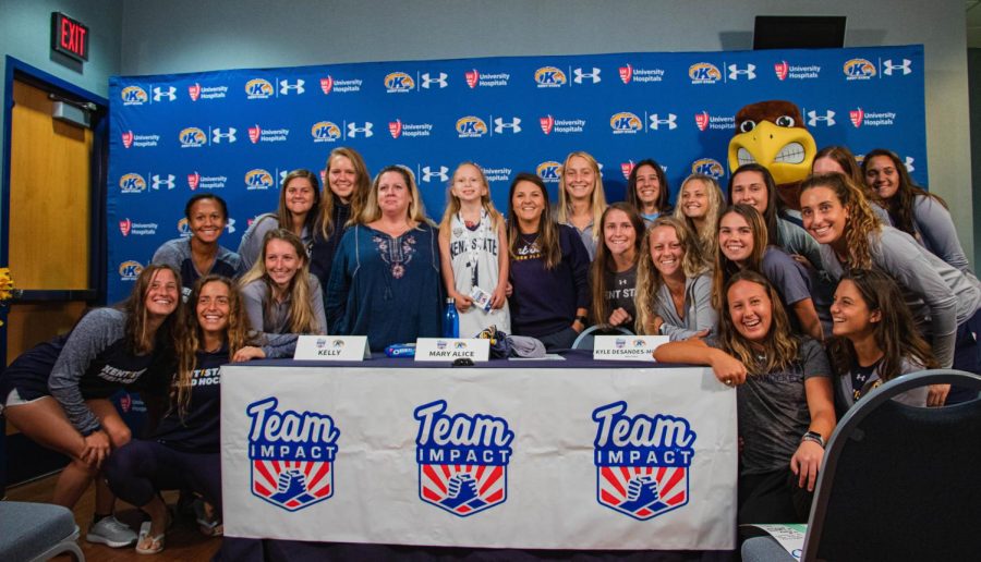 Mary Alice Tryda (center), her mother Kelly Tryda (center left) and Coach Kyle DeSandes-Moyer (center right) pose with the Kent State Field Hockey team. This picture was taken shortly after Mary Alice signed onto the team at the Kent State Mac Center. Sept 25, 2019.