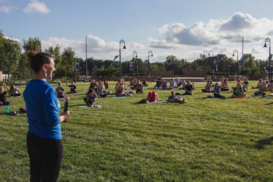 Director of Kent State of Wellness speaks to the yoga crowd Wednesday Sept. 4, 2019. Graduate student of higher education and student affairs, Rylie Woods, led a meditation after the yoga. "It's just an initiative to get people out and moving," Woods said about Yoga on the Green. 