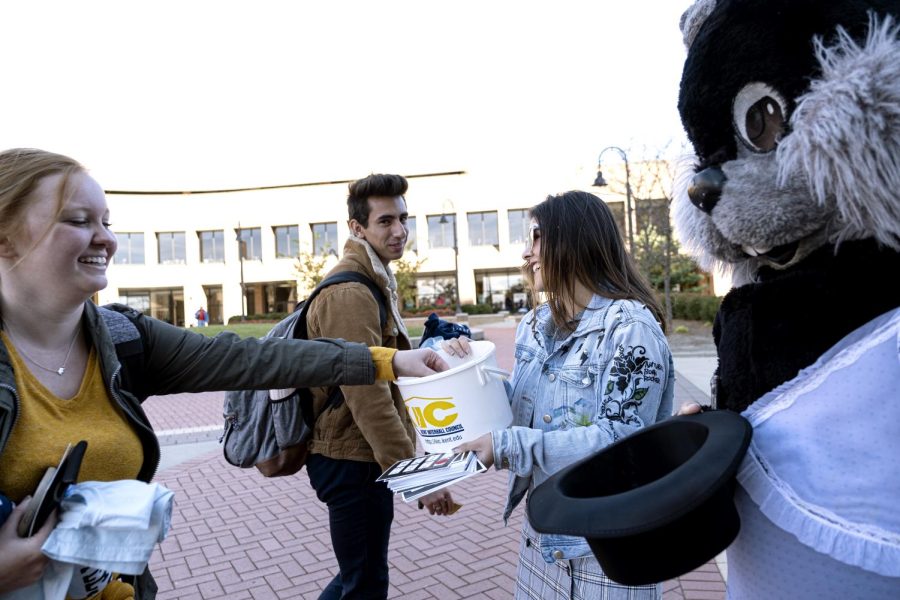 Junior visual communication design major Sarita Kumde and freshman architecture major Adryan Reyes (wearing the "Condom Fairy" costume) give free condoms to junior speech pathology major Breanna Lokken and sophomore early childhood education major Nick Miller during Kent Interhall Council's Condoms of the K at Risman Plaza on Monday, Oct. 21, 2019. 