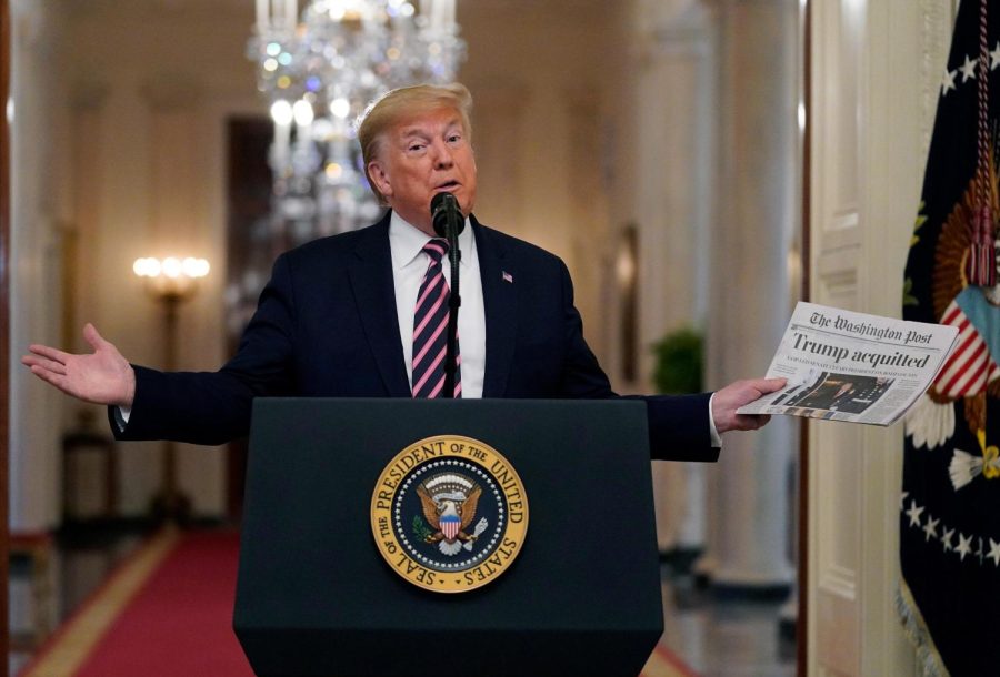 President Donald Trump holds up a newspaper with a headline that reads "Trump acquitted" as he speaks in the East Room of the White House, Thursday, Feb. 6, 2020, in Washington. (AP Photo/Evan Vucci)