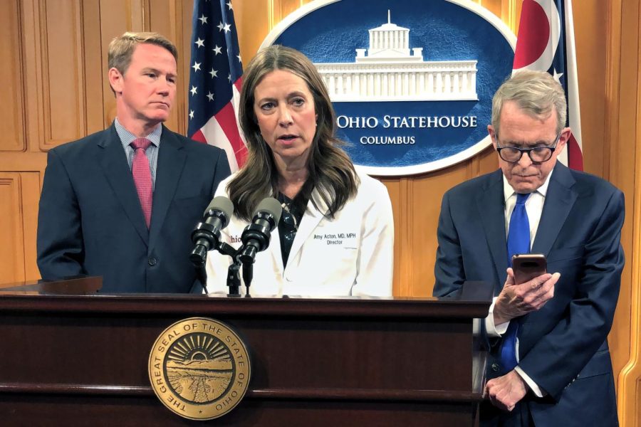 Dr. Amy Acton, Ohio Department of Health Director, center, discusses the confirmation of Ohio's first three cases of coronavirus, as Gov. Mike DeWine, right, studies an update on the cases provided to him during a news conference, Monday, March 9, 2020, in Columbus, Ohio. Lt. Gov. Jon Husted is at left. Acton said the state is "leaning in and taking an aggressive approach" to combating the disease. (AP Photo/Andrew Welsh-Huggins)