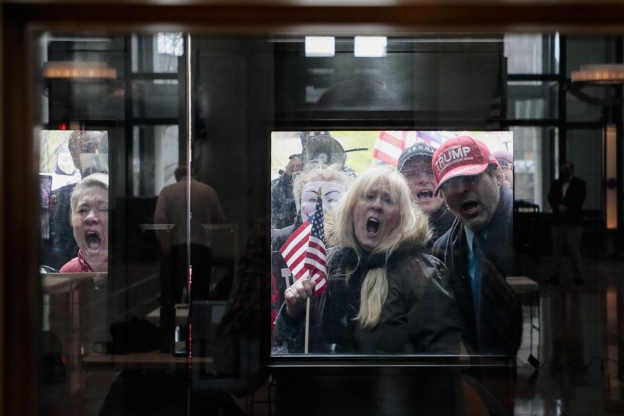 Protesters stand outside the Statehouse Atrium where reporters listen during the State of Ohio's Coronavirus response update on Monday, April 13, 2020 at the Ohio Statehouse in Columbus, Ohio. About 100 protesters assembled outside the building during Gov. Mike DeWine's weekday update on the state's response to the COVID-19 pandemic, upset that the state remains under a Stay-At-Home order and that non-essential businesses remain closed. (Joshua A. Bickel/The Columbus Dispatch via AP)