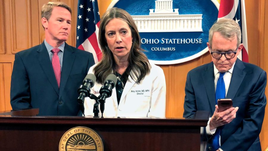 Dr. Amy Acton, the director of the Ohio Department of Health, center, discusses the confirmation of Ohio's first three cases of coronavirus, as Gov. Mike DeWine, right, studies an update on the cases provided to him during a news conference, Monday, March 9, 2020, in Columbus, Ohio. Lt. Gov. Jon Husted is at left. Acton said the state is "leaning in and taking an aggressive approach" to combating the disease. (AP Photo/Andrew Welsh-Huggins)