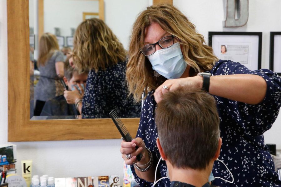 Denise Gravitt, top cuts the hair of client Lisa Murray, bottom, at her salon, Beehive Salon, Friday, May 1, 2020, in Edmond, Okla., the first day hair salons have been allowed to reopen in Edmond following shutdowns due to coronavirus concerns. (AP Photo/Sue Ogrocki)