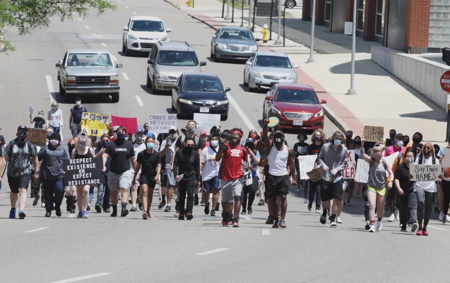 Davonta'e Winchester, wearing a red shirt, shouts into a megaphone as he leads about 100 marchers south on S. High St. in Akron toward the Harold K. Stubbs Justice Center June 7, 2020. The group looped out of downtown through the University of Akron campus to the east side, then made their way back downtown.