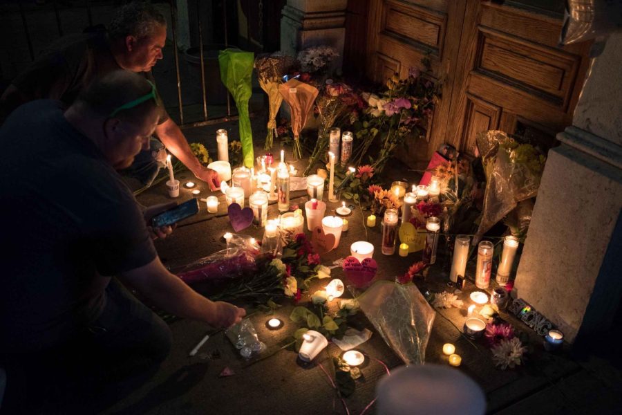 Two men light candles at a makeshift memorial as they take part of a candle lit vigil in honor of those who lost their lives or were wounded in a shooting in Dayton, Ohio on August 4, 2019.