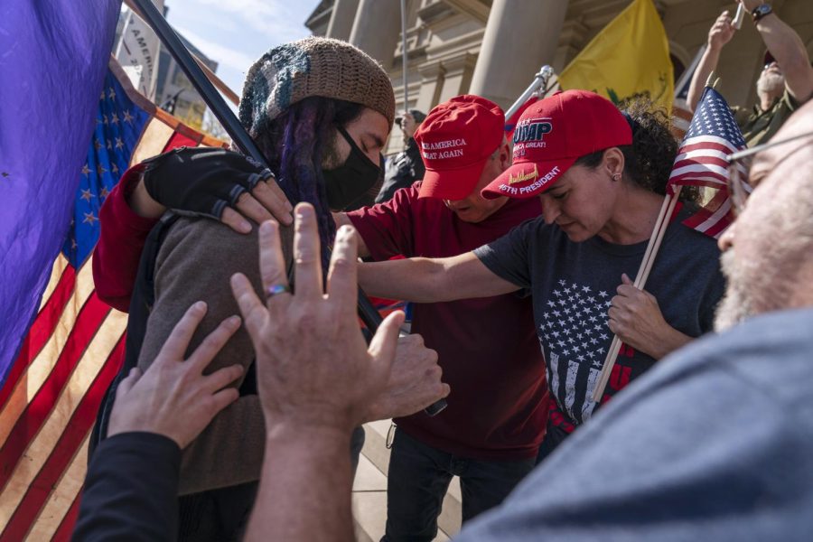 Trump supporters demonstrating during the election results, at right, pray with a counter protester after the presidential election was called for Joe Biden outside the State Capitol in Lansing, Mich., Saturday, Nov. 7, 2020. (AP Photo/David Goldman)