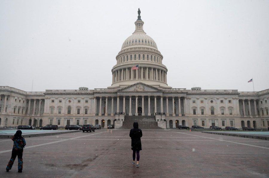 People walk past the US Capitol in Washington, DC on December 16, 2020. - Congressional leaders on December 16, 2020 said they were nearing a long-awaited agreement on a stimulus package for the US economy, while the Federal Reserve is set to provide updated forecasts on an uncertain outlook.