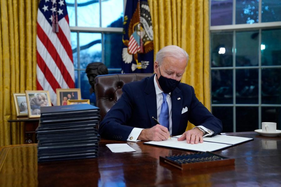 President Joe Biden signs his first executive order in the Oval Office of the White House on Wednesday, Jan. 20, 2021, in Washington. 