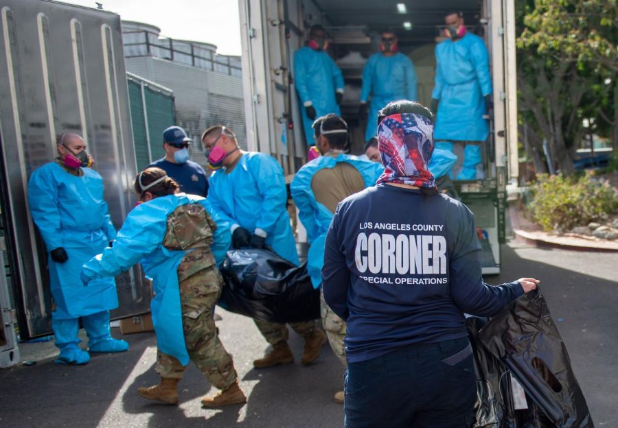 FILE - In this Jan. 12, 2020 file photo, provided by the LA County Dept. of Medical Examiner-Coroner Elizabeth "Liz" Napoles, right, works alongside with National Guardsmen who are helping to process the COVID-19 deaths to be placed into temporary storage at LA County Medical Examiner-Coroner Office in Los Angeles. California reported 669 COVID-19 deaths, the second-highest daily death count, on Saturday, Jan. 16, and the nation's most populous county announced it had detected its first case of a more transmissible strain of the coronavirus. Public health authorities in Los Angeles County confirmed its first case of the variant of COVID-19 first detected in the United Kingdom. It was identified in a man who recently spent time in the county. The man has traveled to Oregon, where he is isolating. (LA County Dept. of Medical Examiner-Coroner via AP, File)