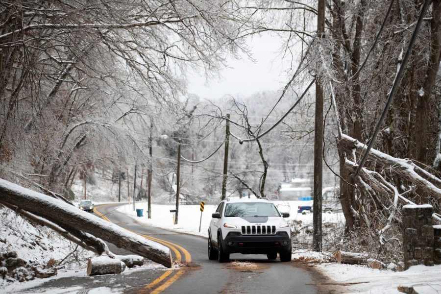 A vehicle navigates around a downed tree along Green Valley Road, as the area continues to deal with the fall out from winter weather on Wednesday, Feb. 17, 2021, in Huntington, W.Va. (Sholten Singer/The Herald-Dispatch via AP)