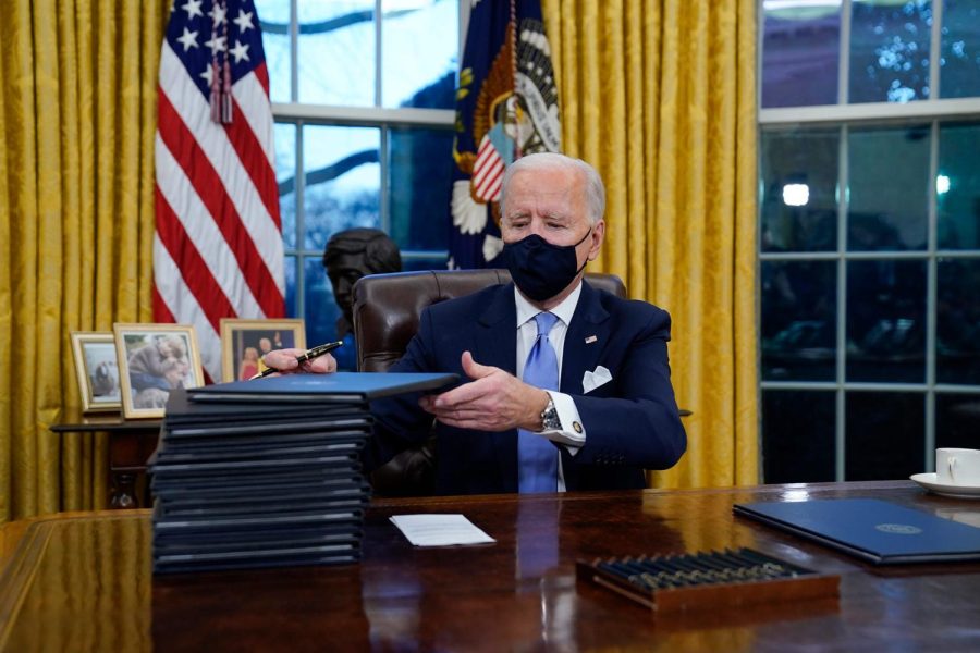 President Joe Biden signs his first executive orders in the Oval Office of the White House on Wednesday, Jan. 20, 2021, in Washington. (AP Photo/Evan Vucci)