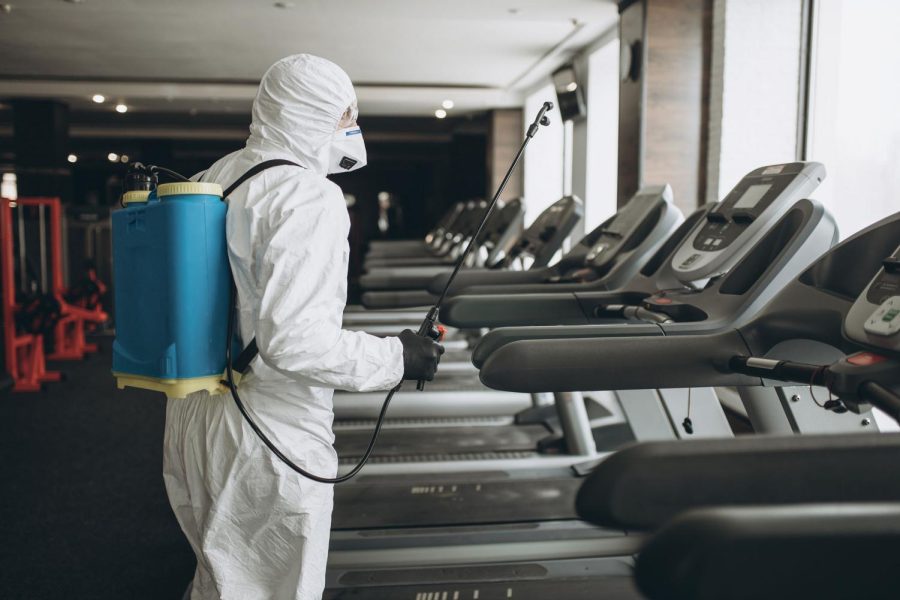 Cleaning and Disinfection in crowded places amid the coronavirus epidemic Gym cleaning and disinfection Infection prevention and control of epidemic. Protective suit and mask and spray bag