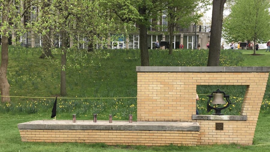 Four candles, representing the four students that died, sit on the Victory Bell, along with a black flag for recently passed Alan Canfora. 