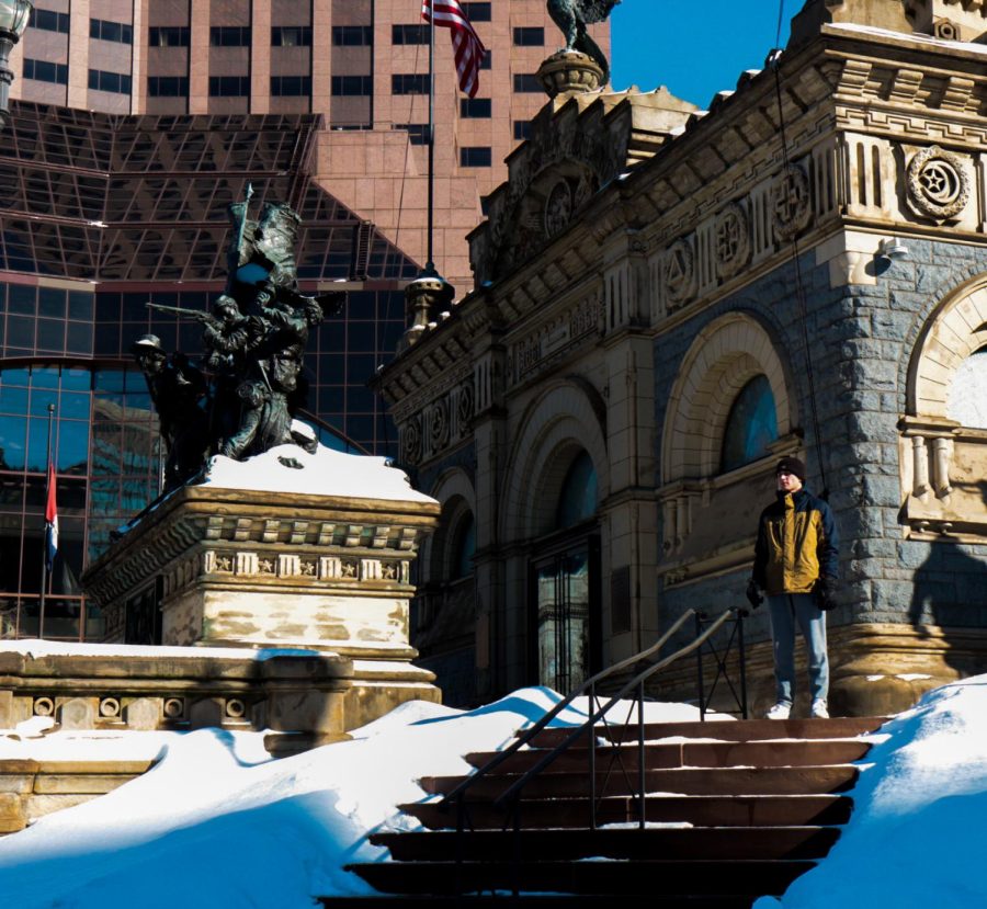 A passerby stands on the Soldiers’ and Sailors’ monument in Cleveland public square overlooking the protest for Palestinian justice on Saturday, Jan. 29. He stood in the sunlight at the top of the stairs for about five minutes listening to one of the speakers before turning back around and going on his way.