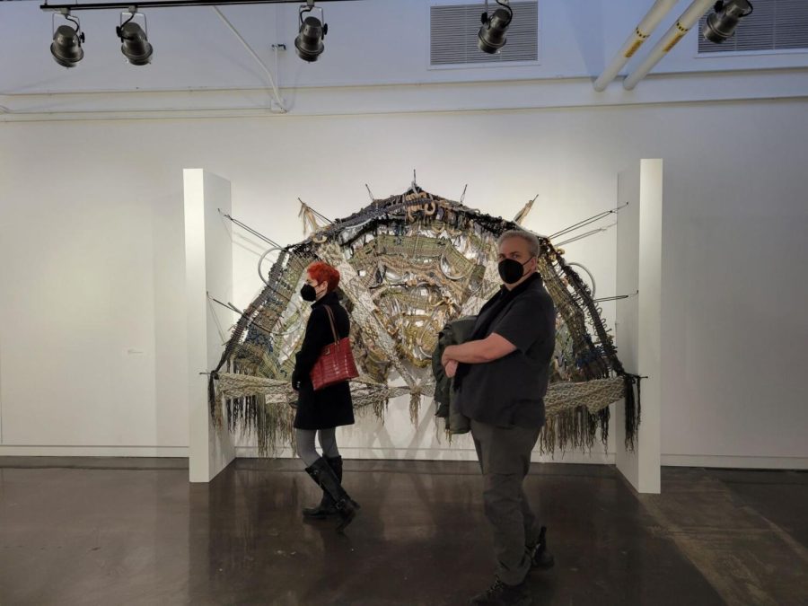 Marie Bukowski (left) and Chester Wilson (right) walk in front of the piece "No Dogs Allowed" at the Line by Line exhibit.