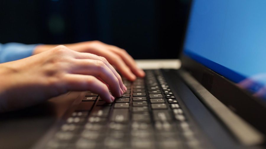 business, education and technology concept - close up of female hands with laptop typing at night