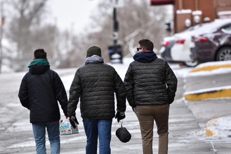 Three Kent State students make for the fraternity houses with a box of drinks during the morning of Fake Paddy's Day.