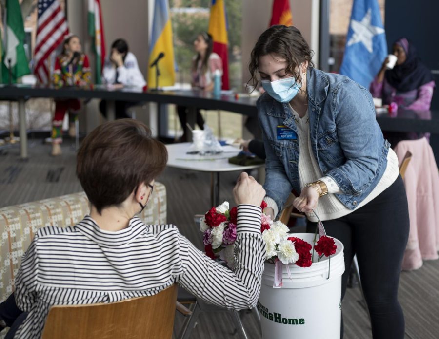 Graduate assistant, Olivia Grahman, hands out carnation flowers to women attending the International Women's Day event inside the Center for Undergraduate Excellence on Mar. 8, 2022. 