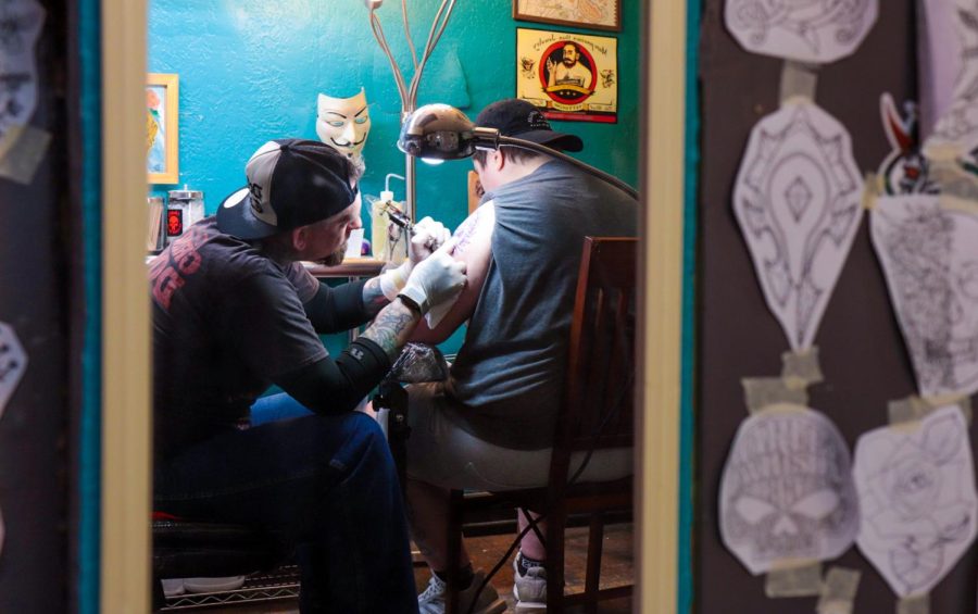 A tattoo artist starts a tattoo on a Kent student's arm at Defiance in downtown Kent.