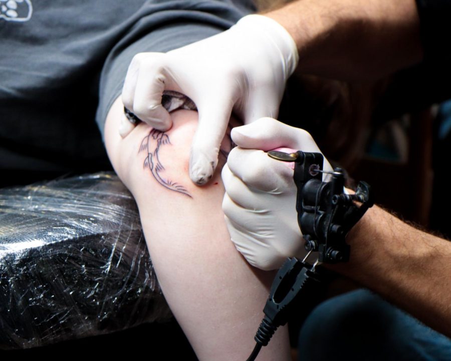 A client gets a tattoo of two coy fish on thier arm at Defiance tattoos in downtown Kent.