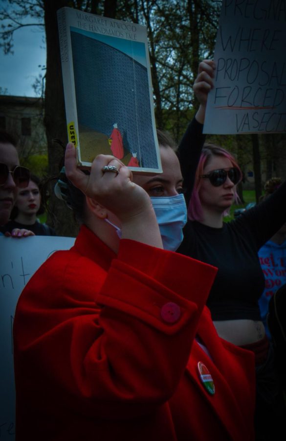 A student dressed in a red coat holds "The Handmaids tale" during the protest for pro-choice rights on Thursday, May 5.