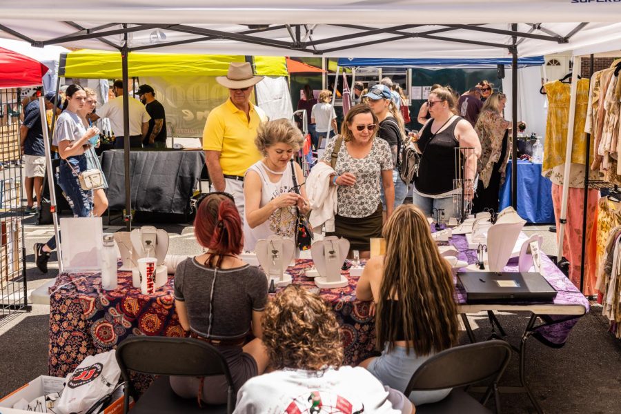 Lauren White (left), owner of Rotten Barbie Boutique at the Kent Art and Wine Festival, June 4, 2022. White is explaining her jewelry making process and the materials she uses to interested customers.