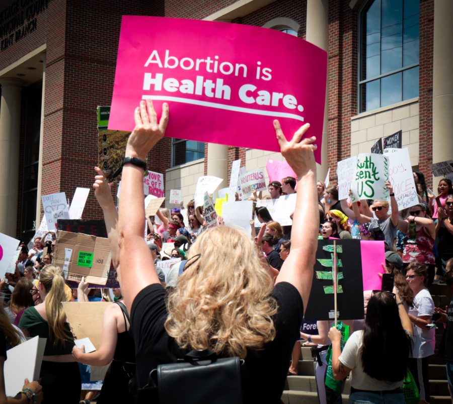 A sign that reads "Abortion is Health Care" is held high in front of the Portage County Municipal Courthouse where protesters gathered at a pro-abortion rights rally on Wednesday, June 29.