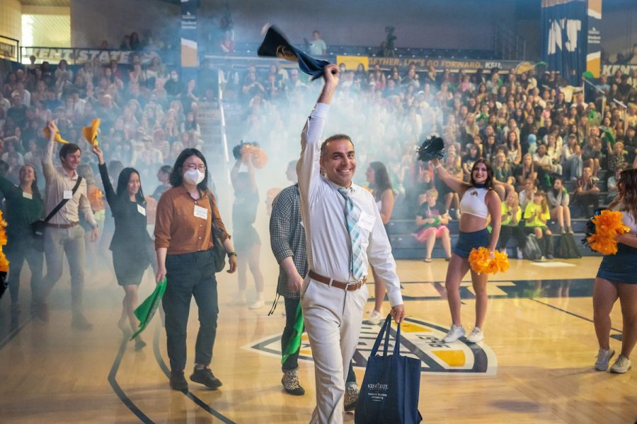 Kent State University faculty members smile and wave rally towels overhead as they cross the court floor at the Memorial Athletic and Convocation (MAC) Center during the university’s 2022 Convocation.