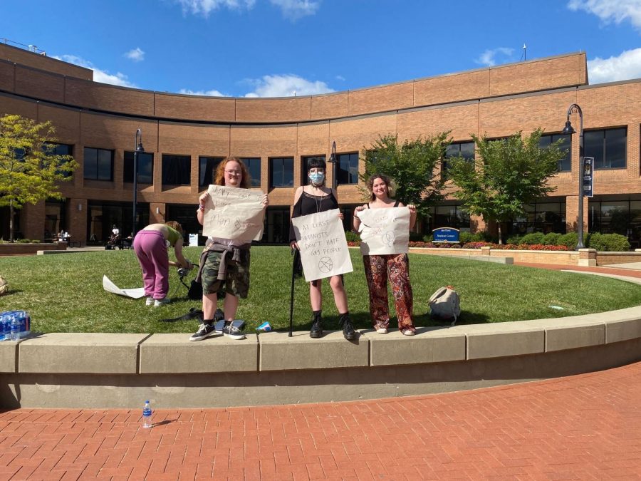 From left to right, students John Ruby Rainey, Olivia Serafim and Karenna Schaller, hold signs during the protest.