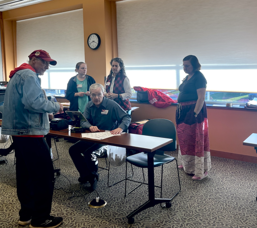 Janice Simmons-Mortiner (back middle) and Sara Moore (right) oversee a polling worker giving a man his ballot at the Kent Free Library on Nov. 8. They are both voting location managers at this precinct.