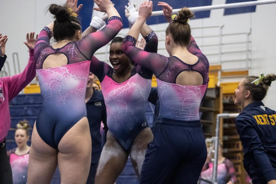 Kyndall Gilbert celebrates with the team as she receives a bar score that ties her with a Cardinals vaulter on Feb. 19, 2023. 